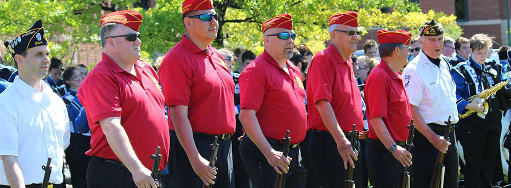 Detachment members in scarlet shirts and red covers marching in a parade